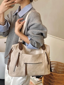 Grand sac cabas beige avec poches zippées multiples et anses marron sur modèle
