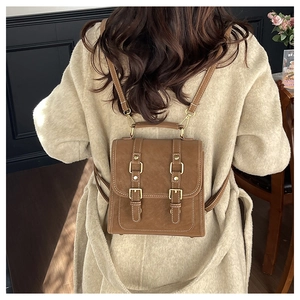 Rear view of a model wearing the brown vintage leather mini backpack with metal buckles
