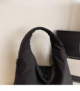 Detail of black quilted nylon tote bag showing textured padded surface and zipper pull
