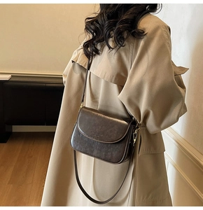 Detailed macro view of dark brown vintage faux leather texture and metallic buckle on bag
