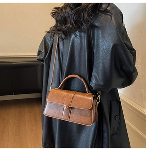 Borsa a baguette vintage marrone con chiusura dorata indossata da modella in ambiente chic
