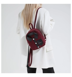Detail of burgundy shirt-shaped backpack featuring a black faux leather collar and buttons