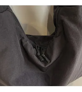 Close-up of black canvas tote zipper with durable metal hardware and rope pullers