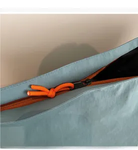 Dettaglio della borsa in tela celeste con cerniera arancione e cordoncino intrecciato