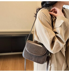 Detail of a vintage dark brown leather shoulder bag with golden metallic buckle closure