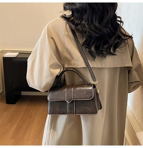 Model wearing a vintage dark brown crossbody bag with a unique V-shaped buckle detail