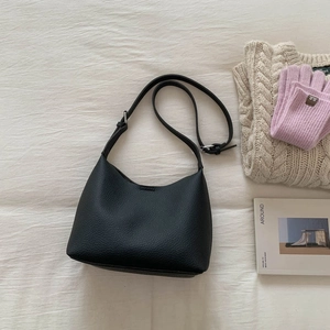 Close-up of black lychee grain leather bucket bag with an adjustable shoulder strap