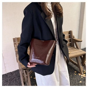Detail of dark brown glossy leather bucket bag showing its adjustable strap and sleek texture