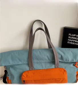 Dettaglio dei manici in tela grigia e cuciture rinforzate su una grande borsa da viaggio