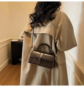Dettaglio borsa a mano retrò in pelle marrone scuro con manico su trench camel