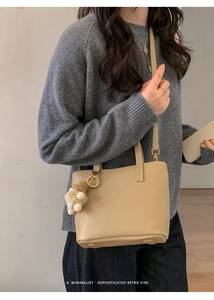 Chic beige bucket bag with lychee texture and plush pendant styled on a model