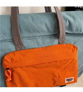 Dettaglio della borsa da viaggio blu e arancione con trama in tessuto stropicciato