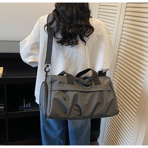 Vue de dos d'une personne portant un grand sac de voyage gris foncé avec bandoulière