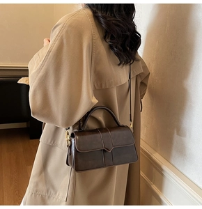 Dettaglio di borsa a tracolla vintage marrone scuro in ecopelle lucida con manico rigido