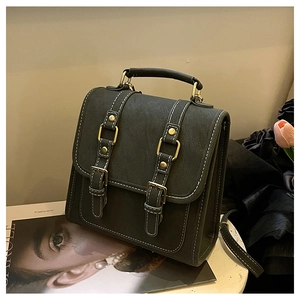 Detail view of dark green retro backpack showing white stitching and gold metal buckles