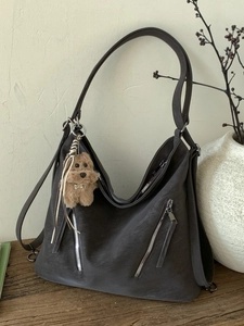 Large dark grey Japanese hobo bag with side zippers and plush dog charm on wooden surface