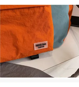 Dettaglio ravvicinato del tessuto in nylon arancione e del logo sulla borsa da viaggio