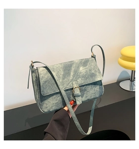 Détail d'un sac à main vintage en denim bleu avec boucle en métal et fine bandoulière