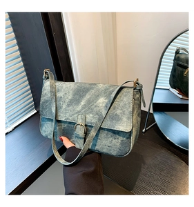 Détail d'un sac bandoulière en denim délavé vintage avec boucle en métal et sangle