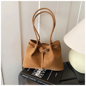 Detail of caramel leather tote bag with buckle strap in a minimalist home setting