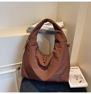Detail of a large dark brown nylon tote bag with unique side knot tie and wide shoulder strap