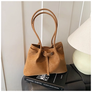 Detailed view of caramel brown tote bag with decorative drawstring and metal buckle