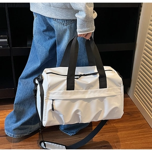 Détail du sac de voyage en toile blanche avec poignées noires et compartiment zippé