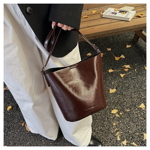 Detail of vintage dark brown glossy leather bucket bag with adjustable shoulder strap