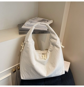 Detail of white hobo bag with pleated nylon texture and silver zippers on a chair