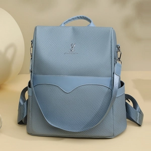 Detail view of fog blue nylon backpack featuring a silver rabbit logo and side pockets