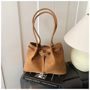 Detail of caramel tote bag with matte leather texture and silver buckle on black seat