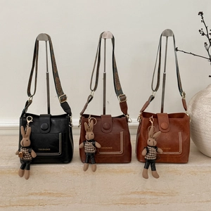 Detail of three PU leather bucket bags with wide ethnic patterned straps and charms