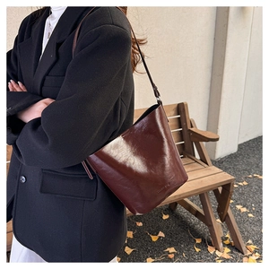 Detail view of a vintage dark brown leather bucket bag on a model in a fall setting