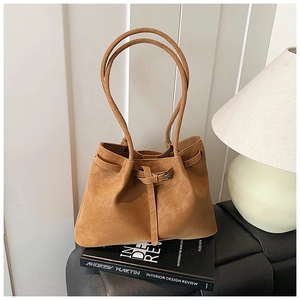 Detail of camel tote bag featuring pleated texture and thin shoulder straps on sofa