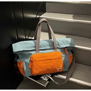 Dettaglio borsa da viaggio blu e arancione con ampie tracolle e tasca frontale a zip