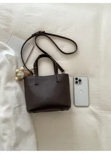 Detail of dark brown lychee pattern leather bucket bag with plush charm and strap