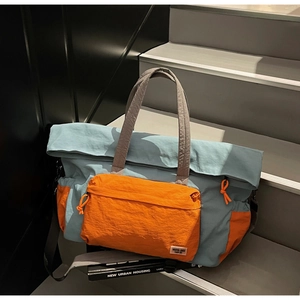 Dettaglio della borsa da viaggio bicolore in nylon grigio-blu e arancione acceso