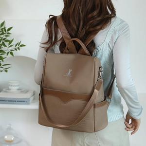 Brown woven backpack with leather trim and metal logo shown in a lifestyle home setting