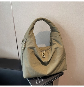 Detail of army green nylon shoulder bag featuring pleated texture and corded zipper pull