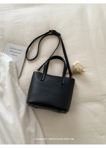 Detail of black lychee grain leather bucket bag with a cute plush bear charm