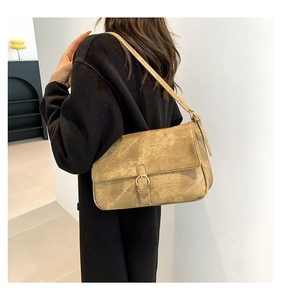 Gros plan d'un sac à bandoulière vintage en cuir marron avec boucle dorée sur un mannequin