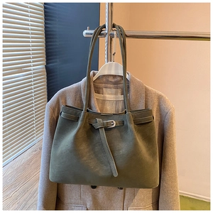 Detail of dark green suede tote bag with silver buckle on a stylish wool blazer