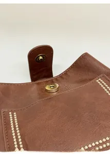 Detail of brown leather bag showing gold magnetic closure and fashion text engraving