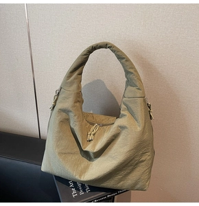 Detail of olive green tote bag showing wrinkled nylon texture and wide shoulder strap