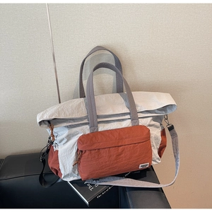 Dettaglio borsa da viaggio in tela beige e rossa con tasche su divano in pelle