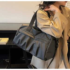 Vue latérale d'un grand sac de voyage noir porté par un mannequin en trench coat