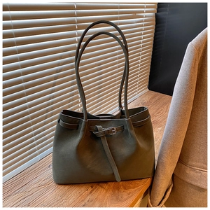 Detailed view of dark green faux suede tote bag with decorative metal buckle and natural folds