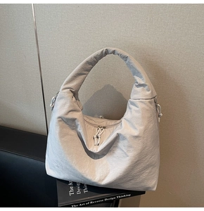 Detail of light grey tote bag featuring crinkled nylon texture and knot zipper pullers