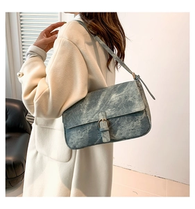 Détail d'un sac à bandoulière vintage bleu texturé avec une boucle à anneau doré