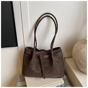 Macro view of dark brown suede tote bag featuring slim leather straps and metal buckle